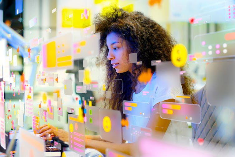 A woman with dark hair looks down with various small images around her.